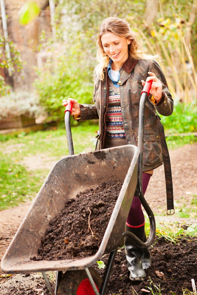 Women emptying a wheelbarrow full of mulch in the garden